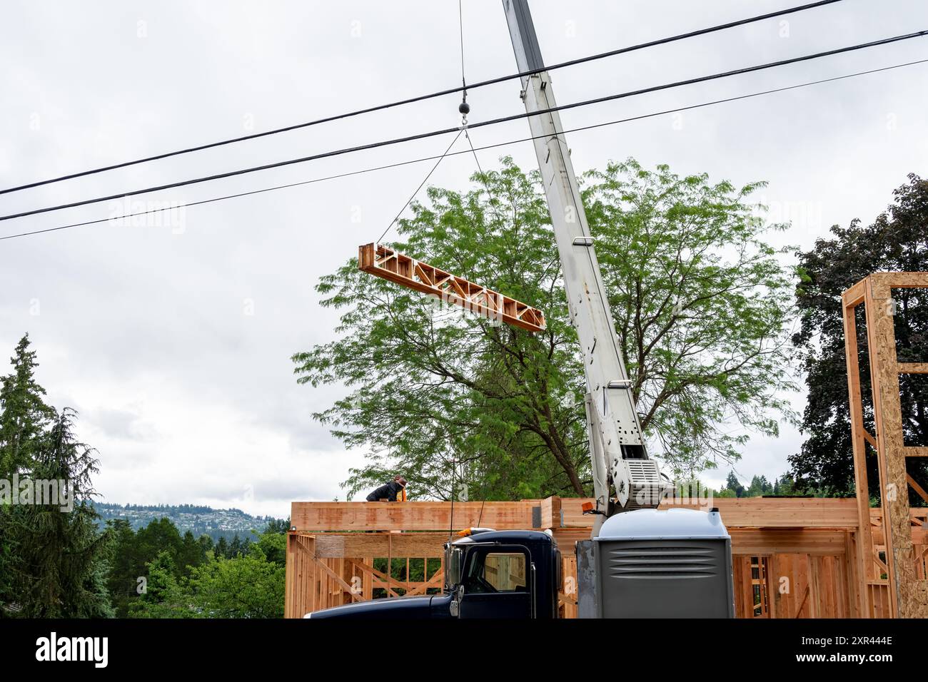 Wohnhausbau, Auslegerkran heben Holzlieferungen, Holzträger, bis zur nächsten Etage des Projekts Stockfoto