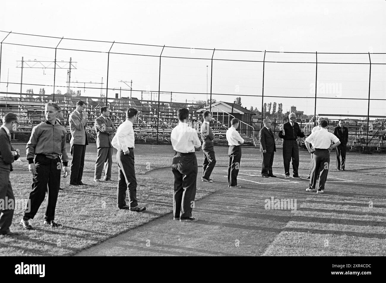 Die Gentlemen-Gruppe erhält eine Erklärung über Softball in einem Stadion, Whizgle Dutch News: Historical Images Tailored for the Future. Erkunden Sie die Vergangenheit der Niederlande mit modernen Perspektiven durch Bilder von niederländischen Agenturen. Verbinden der Ereignisse von gestern mit den Erkenntnissen von morgen. Begeben Sie sich auf eine zeitlose Reise mit Geschichten, die unsere Zukunft prägen. Stockfoto