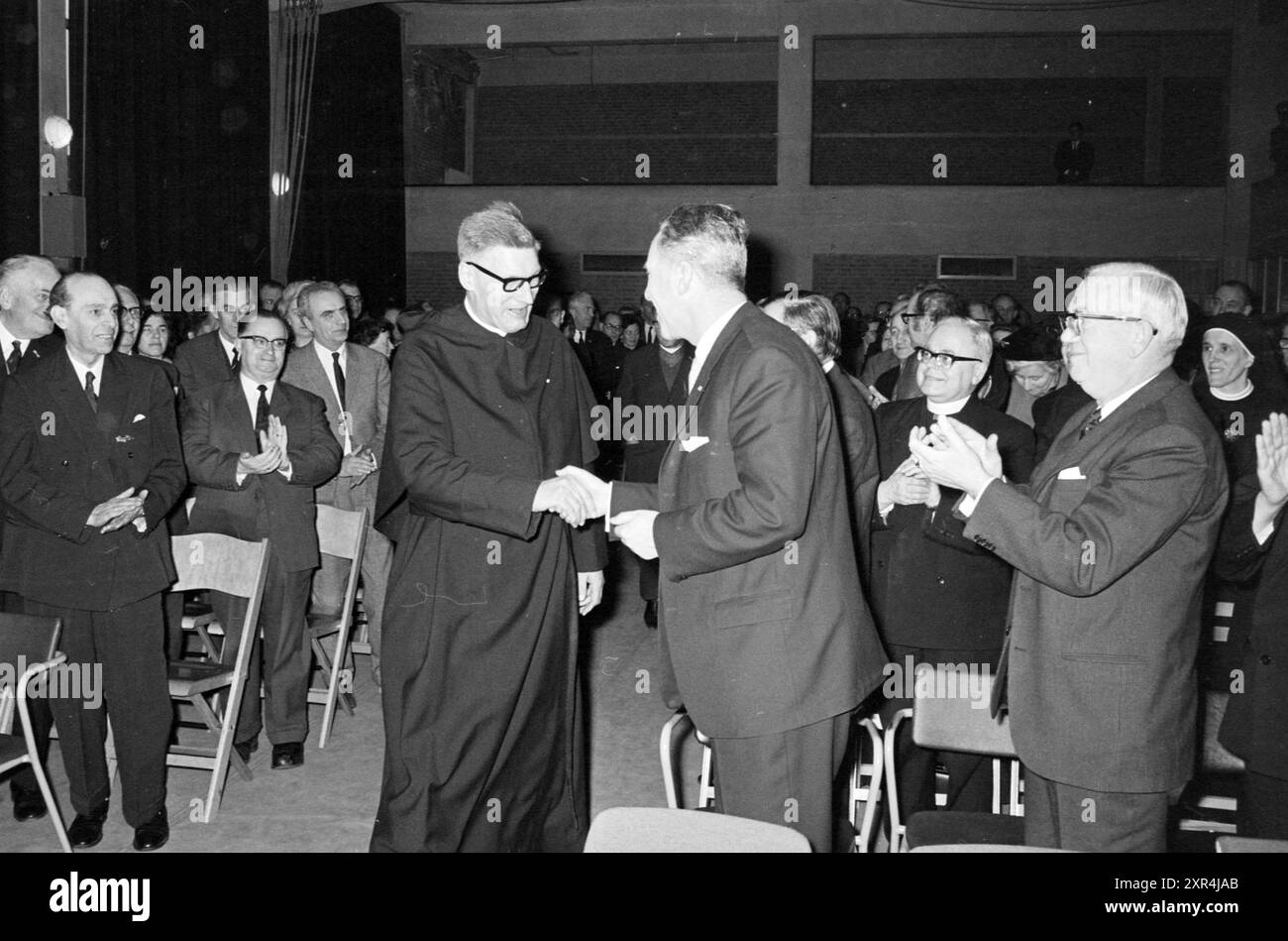 Treffen des katholischen Klerus in einem Gymnasium mit Glückwünschen von einem Priester, Whizgle Dutch News: Historische Bilder zugeschnitten auf die Zukunft. Erkunden Sie die Vergangenheit der Niederlande mit modernen Perspektiven durch Bilder von niederländischen Agenturen. Verbinden der Ereignisse von gestern mit den Erkenntnissen von morgen. Begeben Sie sich auf eine zeitlose Reise mit Geschichten, die unsere Zukunft prägen. Stockfoto