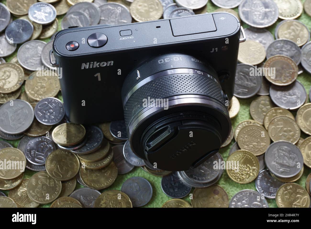 Terengganu, Malaysia - 24. August 2024: Nahaufnahme der schwarzen nikon 1 j1 spiegellosen Kamera auf verstreuten malaysischen Münzen Stockfoto