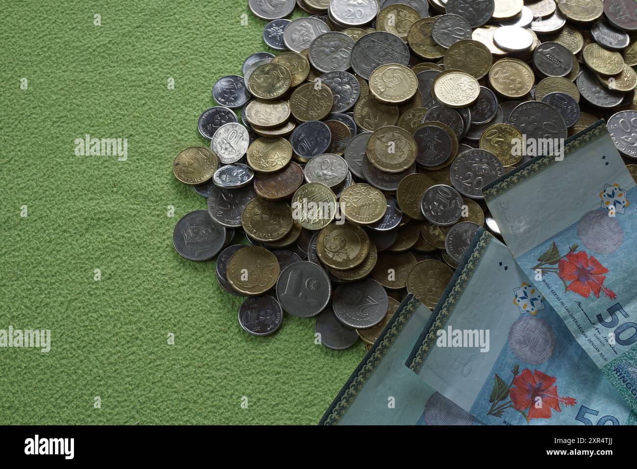 Terengganu, Malaysia - 24. August 2024 : Nahaufnahme der verstreuten malaysischen Münzen und 50 Ringgit malaysisches Geld auf grünem Hintergrund Stockfoto