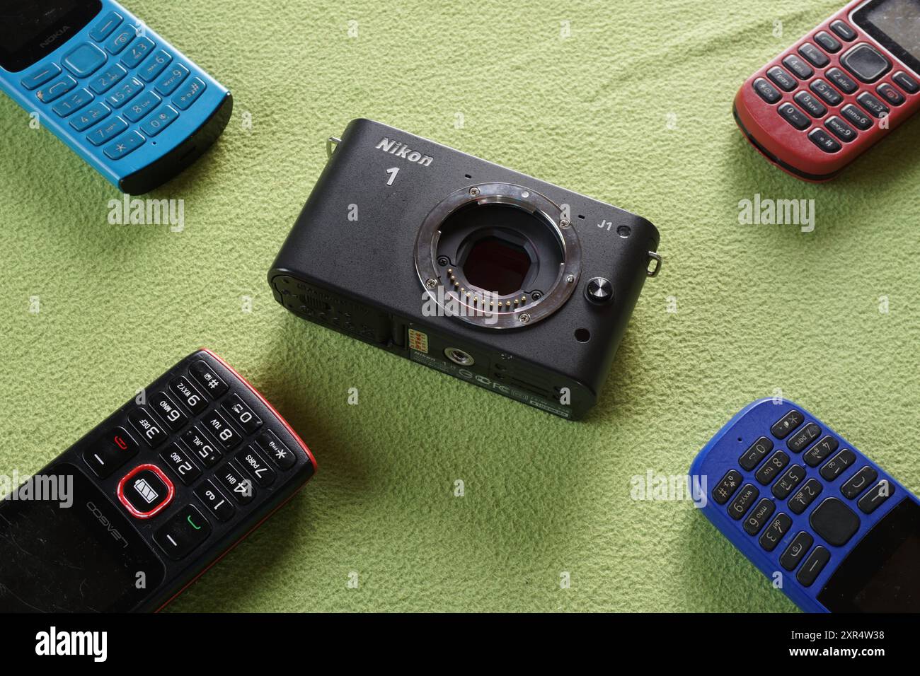 Terengganu, Malaysia - 24. August 2024 : Nahaufnahme der spiegellosen nikon 1 j1 Kamera und verschiedener Tastaturtelefone auf grünem Hintergrund Stockfoto