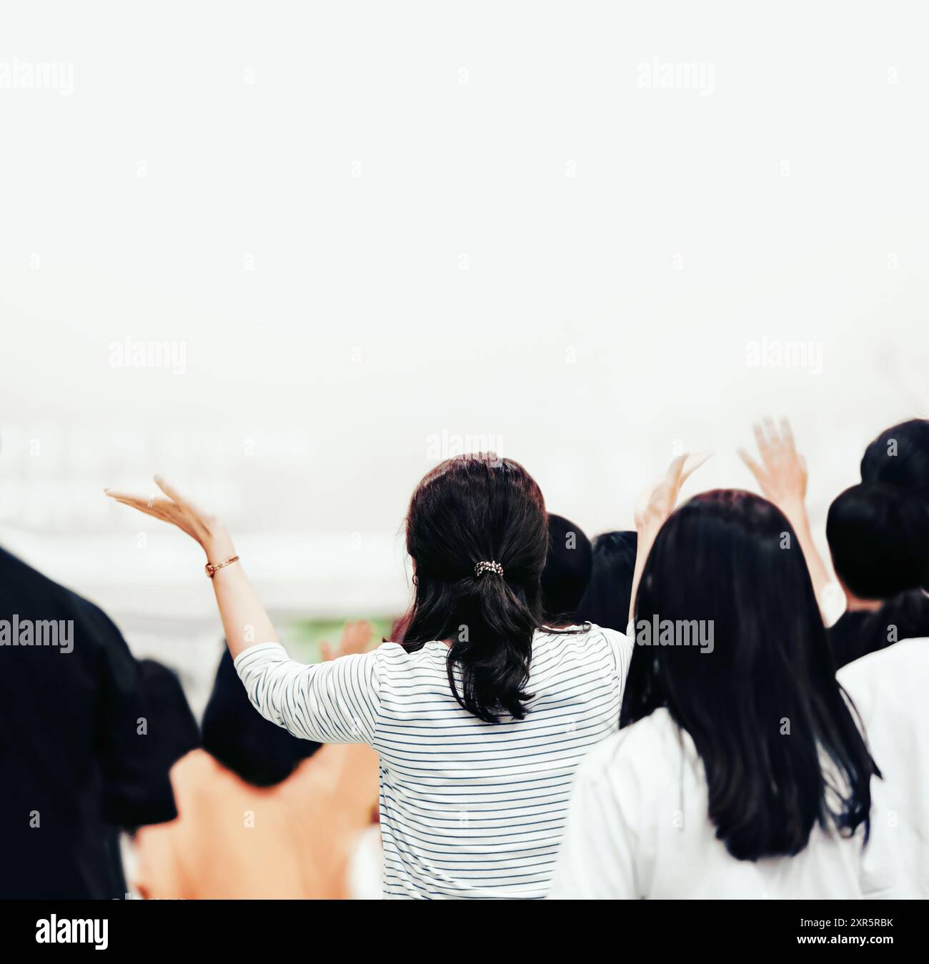 Leidenschaftliche christliche Frau, die beide Hände in Lobpreis und Gebet erhebt, Heiliger Geist erfüllte Anbetung und kirchlicher Hintergrund Stockfoto