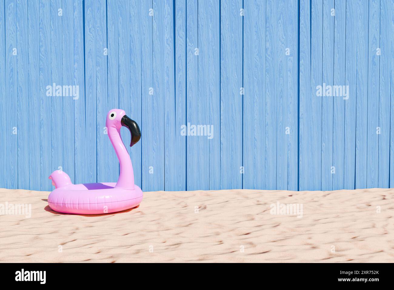 3D-Rendering eines pinkfarbenen aufblasbaren Flamingos auf Sandstrand-Gelände mit strukturiertem blauem Holzhintergrund, Sommerspaß-Konzept. Stockfoto