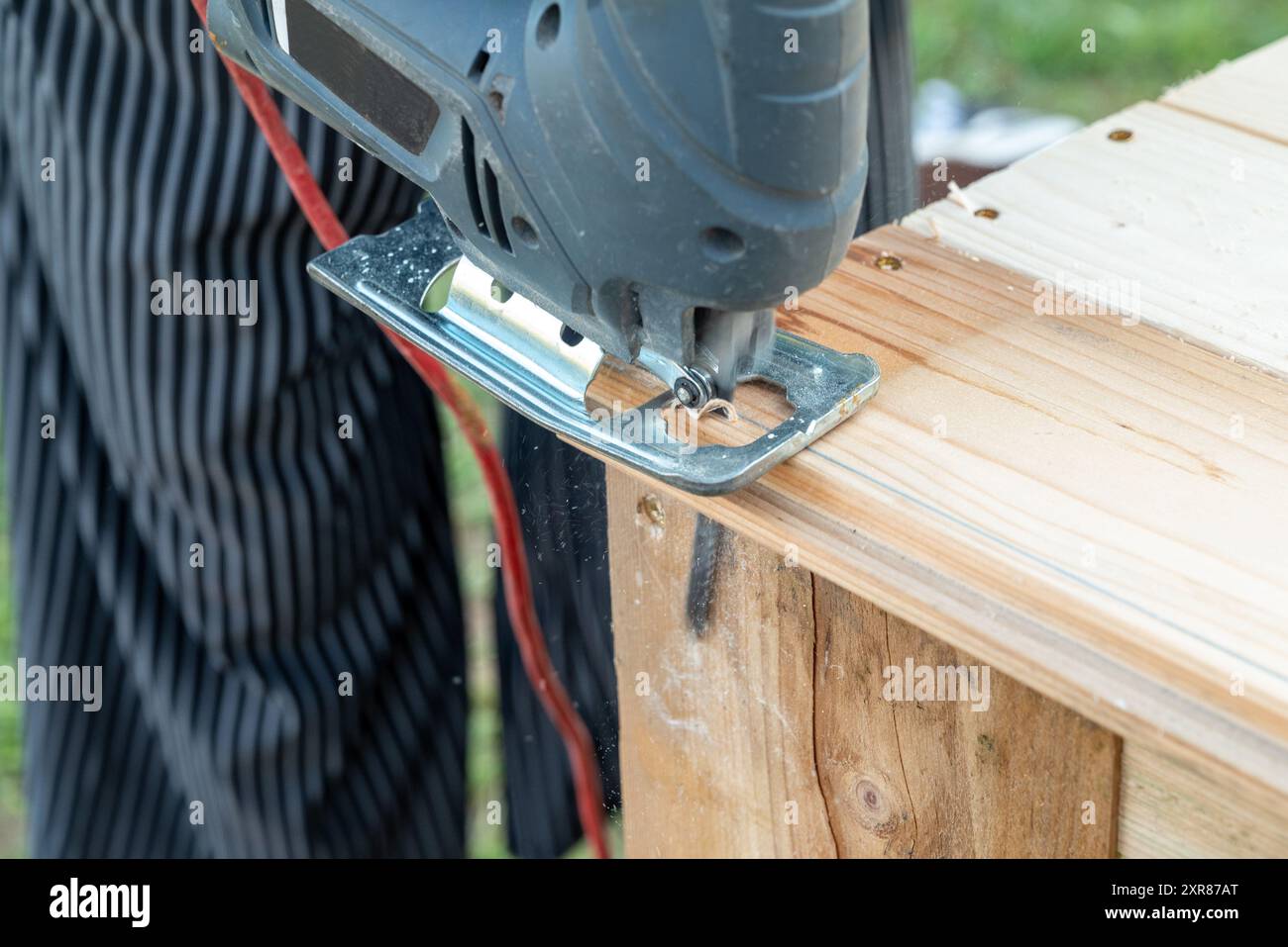 Ein Bastler Heimwerker, der mit einer Stichsäge eine Holzdiele schneidet - eine Art Elektrowerkzeug mit einer Hubklinge Stockfoto