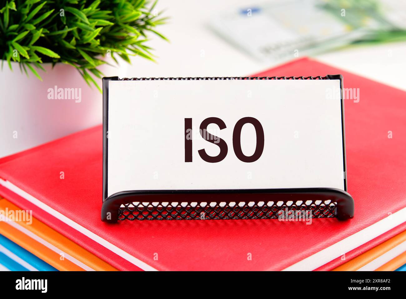 Business- und ISO-Konzept. ISO-Normen Qualitätskontrollsymbol. Konzeptwort ISO auf einer Visitenkarte, die in einem Ständer auf einem Notizblock steht Stockfoto
