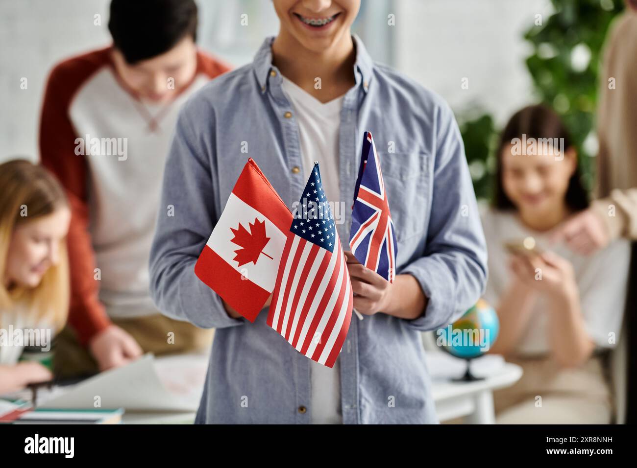 Teen hält Flaggen für Kanada, USA und Großbritannien im UN-Modell. Stockfoto
