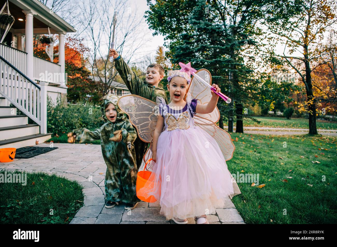 Kinder in Feen- und Dinosaurierkostümen, fröhlich mit Trick-or-Treatment Stockfoto
