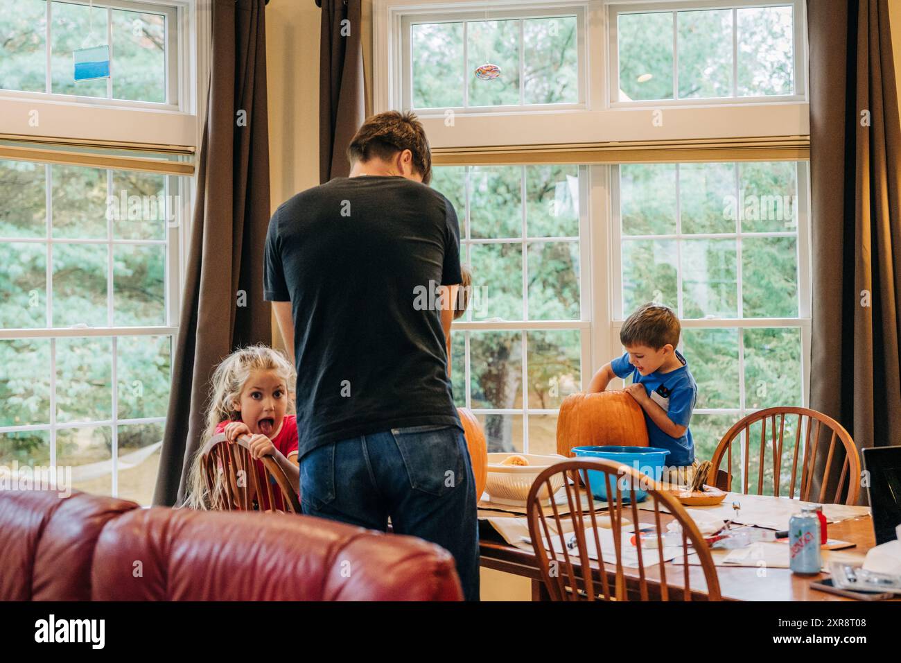 Familie schnitzt Kürbisse drinnen, Kinder- und Vater-Aktivitäten Stockfoto