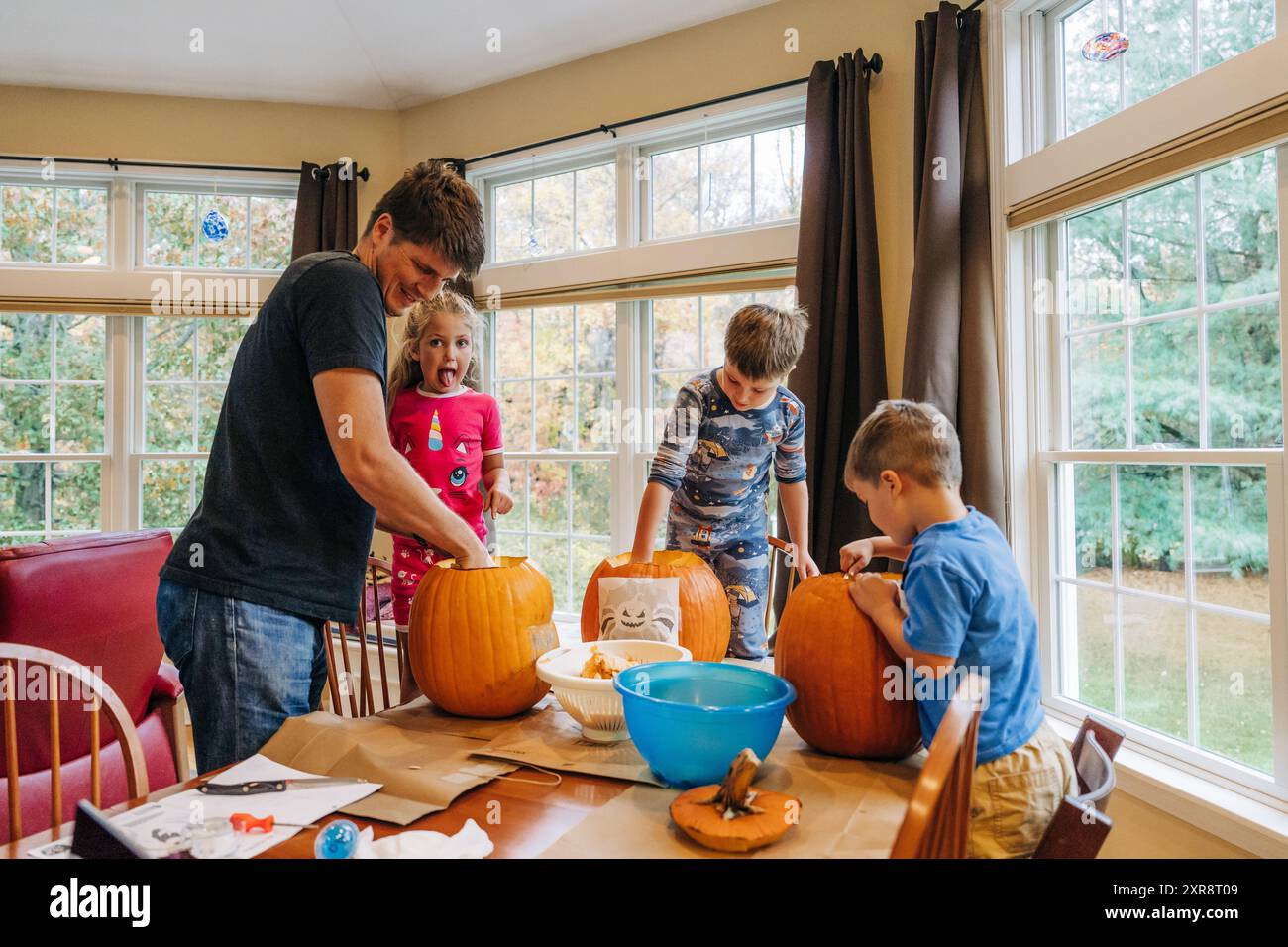 Familie schnitzt Kürbisse drinnen, Kinder- und Vater-Aktivitäten Stockfoto