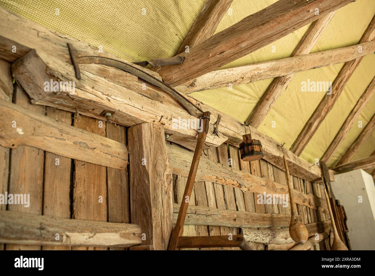 An der Wand in der Scheune hing eine antike Sense. Alte landwirtschaftliche Werkzeuge. Hochwertiges Foto Stockfoto