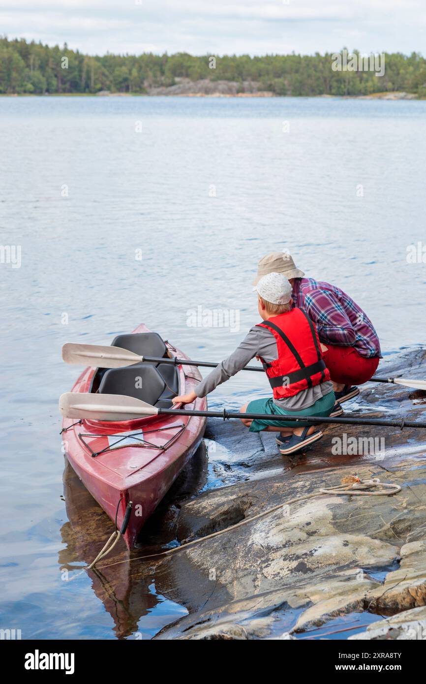 Vater unterrichtet seinen Sohn für Kajakfahren am Meer mit Paddeln zum Kajakfahren am Meer, Kanu fahren, Bootfahren in der Ostsee während der Familienferien Stockfoto