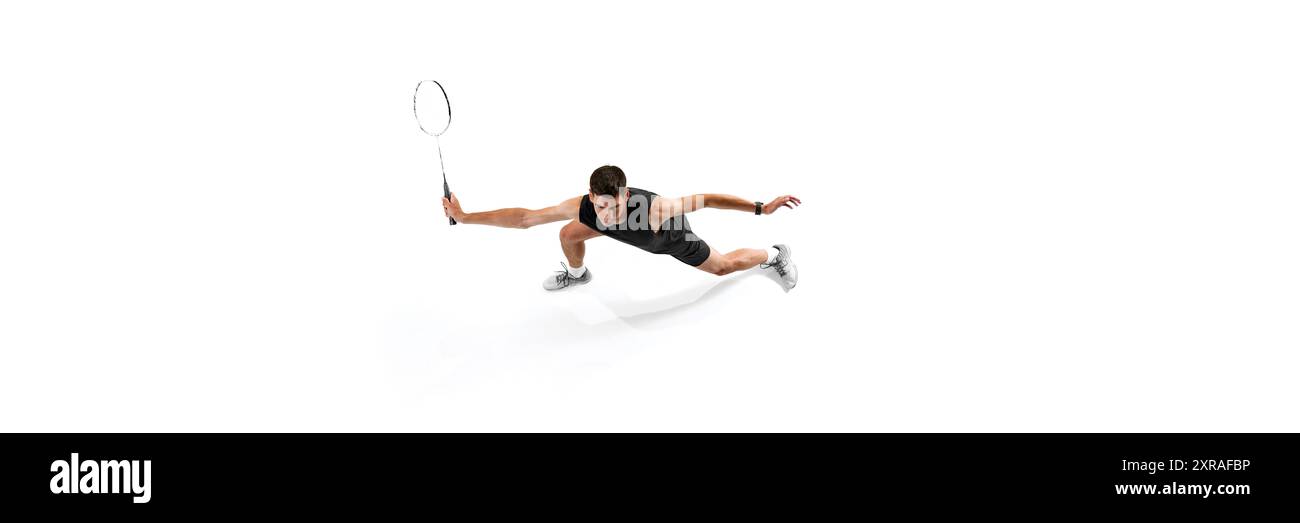 Intensives Training. Blick von oben auf jungen Mann, Badmintonspieler in Uniform in Bewegung mit Schläger, wachsende Fähigkeiten und Fokus auf weiß Stockfoto