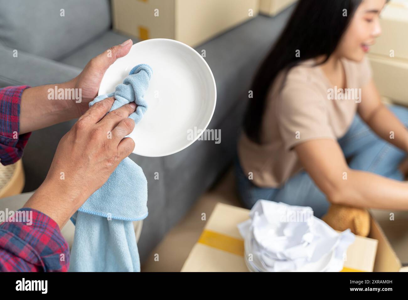 Junges Paar in einer neuen Wohnung, zieht in ein neues Haus, sitzt auf dem Boden und entspannt sich nach dem Putzen und Auspacken des Geschirrs. Stockfoto