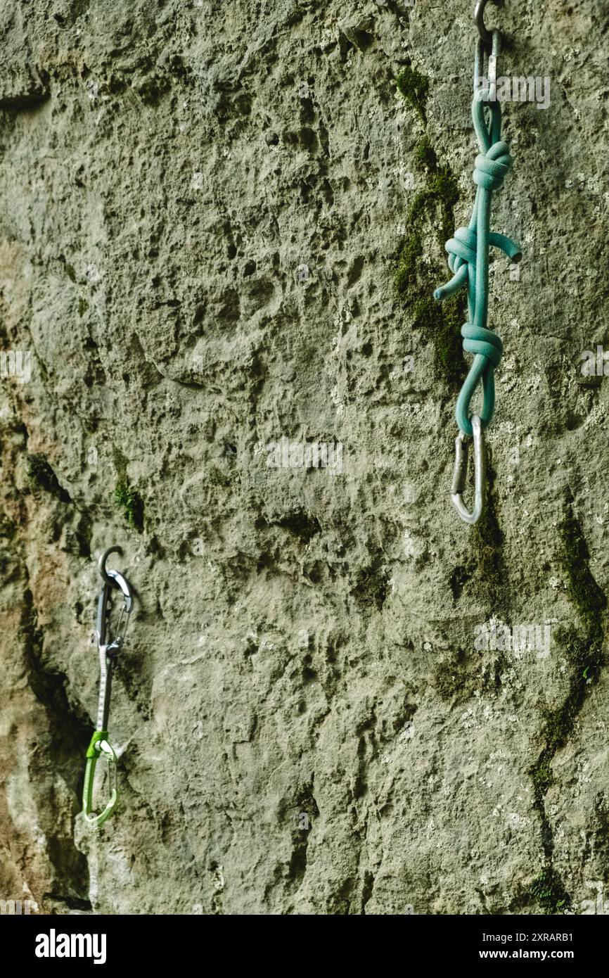 Karabiner vom Typ T sind an einer vertikalen Kletterwand an einem Kletterplatz im Freien im Fels verankert. Stockfoto