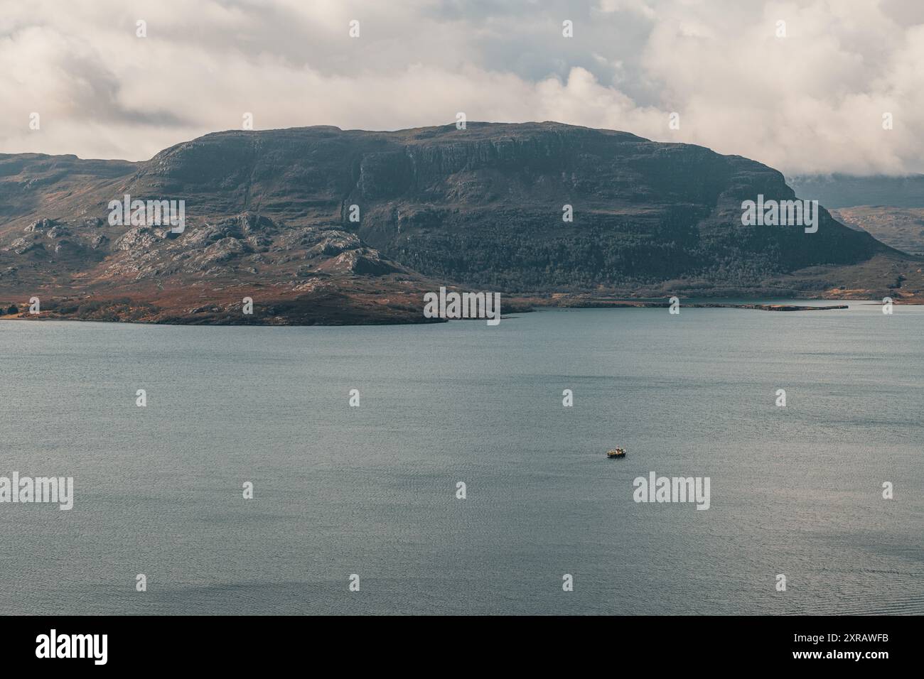 Ein Panoramablick auf einen Berg von den schottischen Highlands im Hintergrund eines Sees mit Segelboot an einem bewölkten Tag Stockfoto
