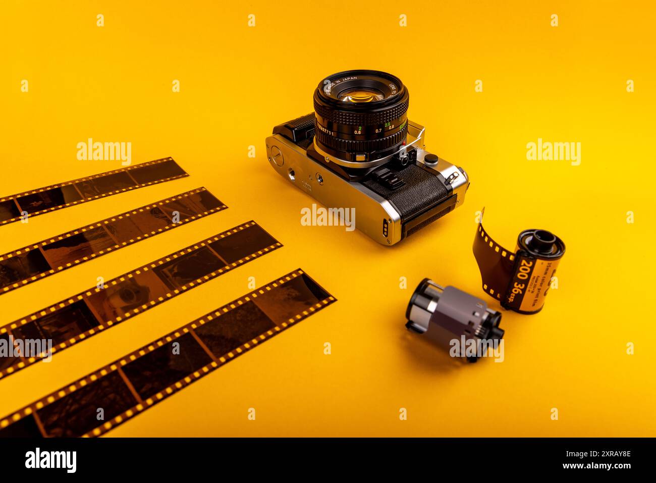 Nahaufnahme einer alten Kamera mit 35-mm-Filmrollen auf gelbem Hintergrund, die das Wesen der analogen Fotografie einfangen. Stockfoto