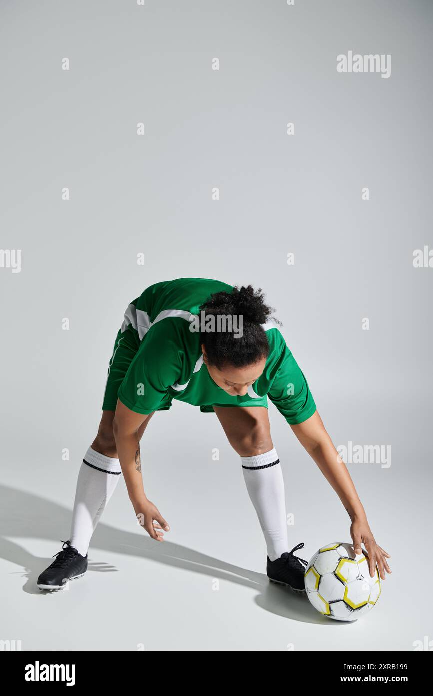 Eine Sportlerin in grüner Uniform kontrolliert den Ball während eines Fußballspiels. Stockfoto