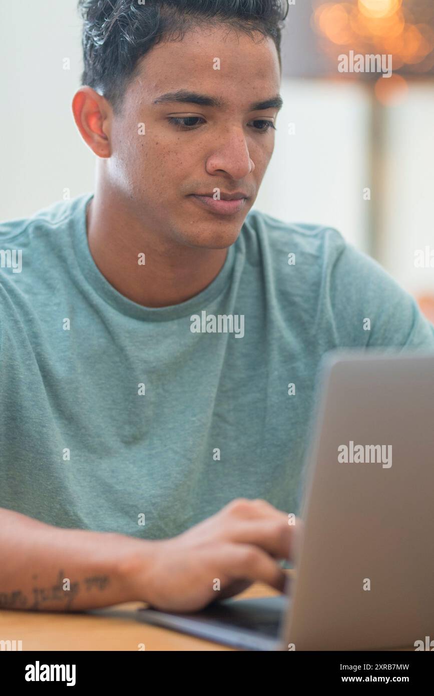 Lächelnder junger Mann Freiberufler mit Laptop Online-Studium von zu Hause aus arbeiten, glücklich casual Hipster Kerl tippen auf pc Notebook Surfen Internet Blick auf Bildschirm genießen entfernten Job sitzen am Tisch Stockfoto