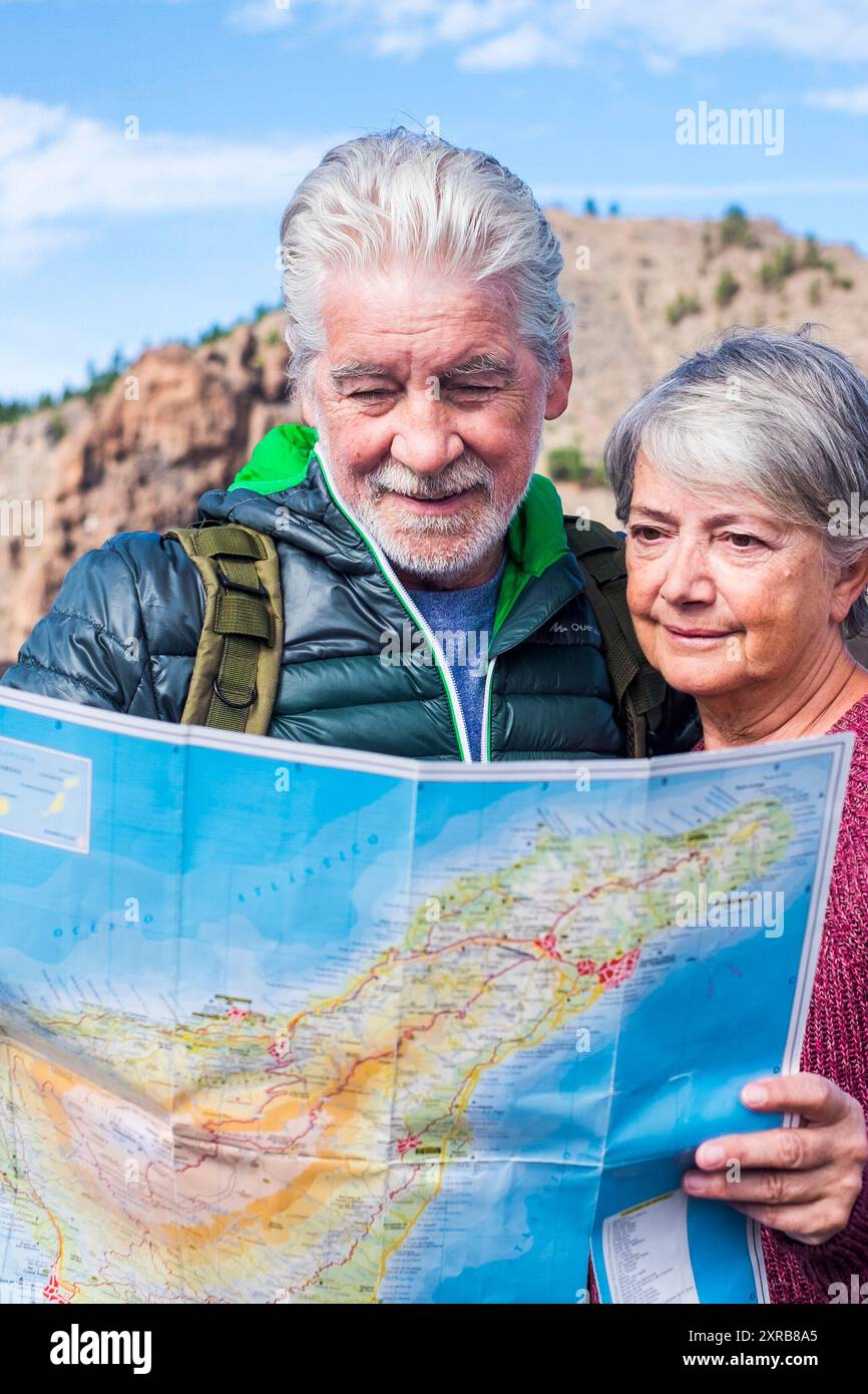 Junge Senioren genießen gemeinsam Reisen und aktiven Lebensstil - zwei alte Männer und Frauen, die unterwegs eine Karte suchen - Alternativleben im Ruhestand und Bergwanderurlaub im Freien Stockfoto