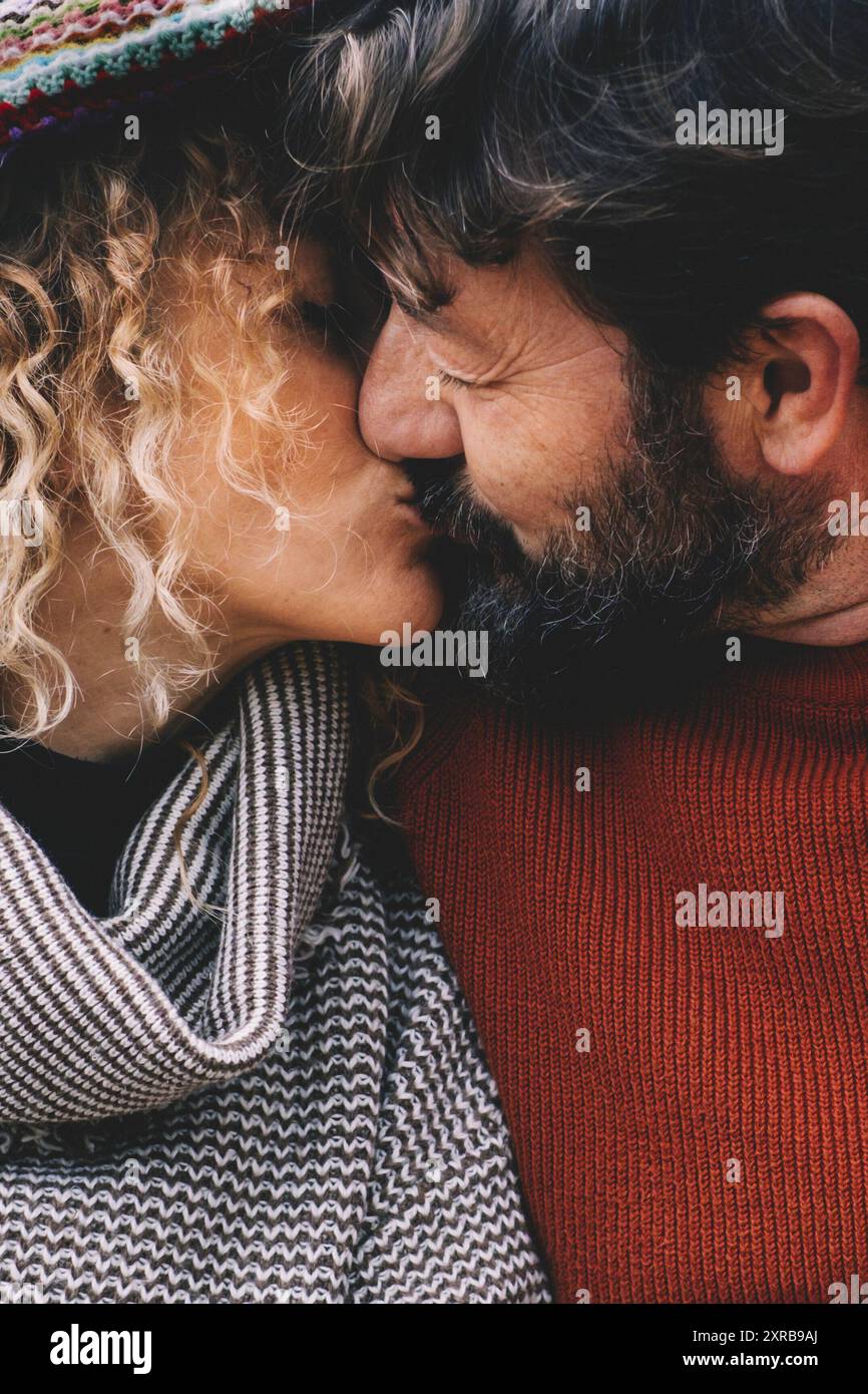 Verliebtes Paar küsst sich unter einer bunten Wolldecke. Das Konzept reifer Menschen in Beziehung und Leben für immer. Mann küsst Frau mit Romantik. Das Leben mit Liebe genießen Stockfoto