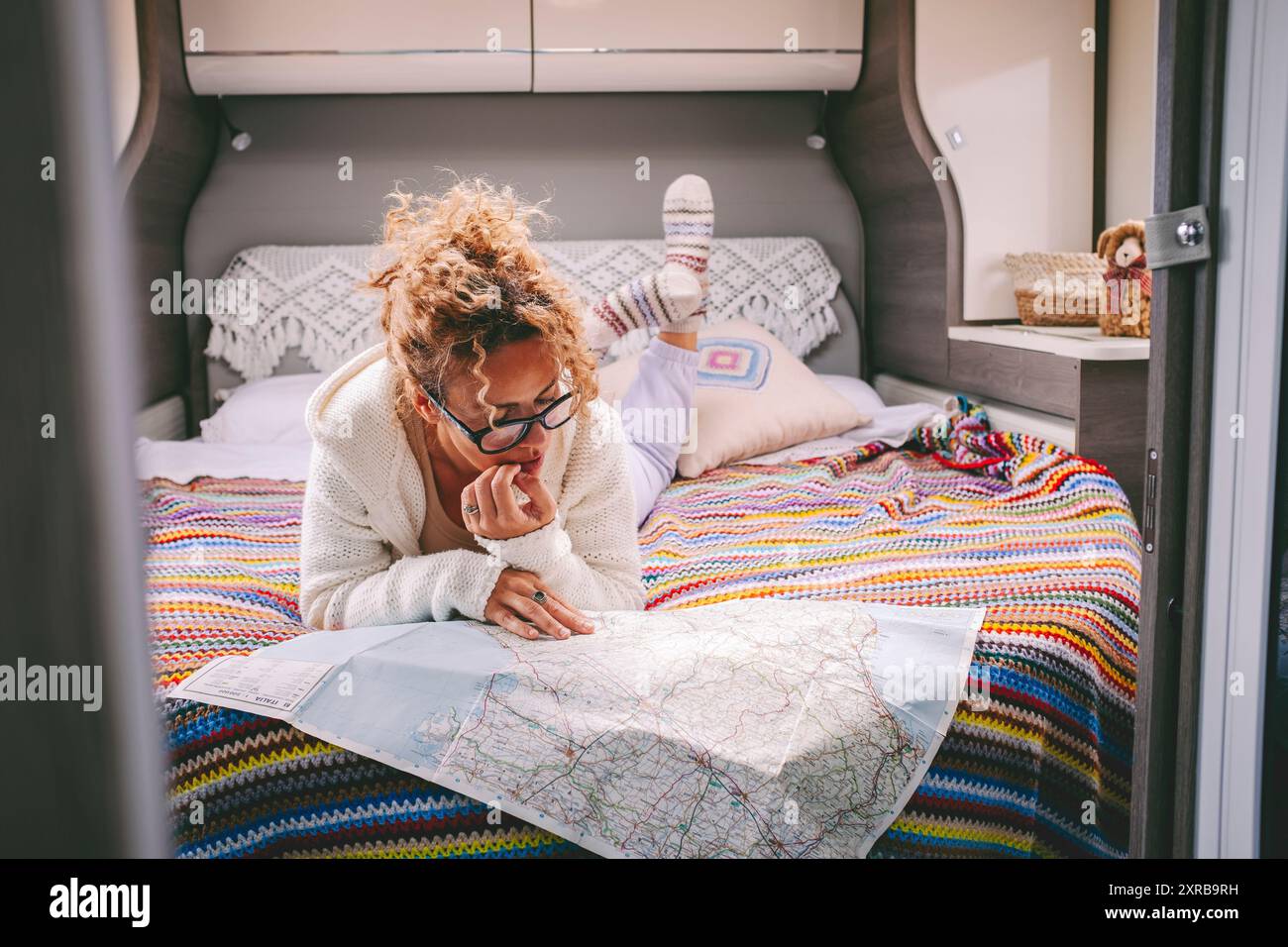 Weibliche Reisende entspannen sich in der Innenausstattung des Wohnmobils und schauen sich die Straßenkarte auf Papier an, um das nächste Reiseziel zu finden. Reise und Abenteuer im Vanlife-Lifestyle. Eine Frau in der Freizeit im Innenraum-Van Stockfoto