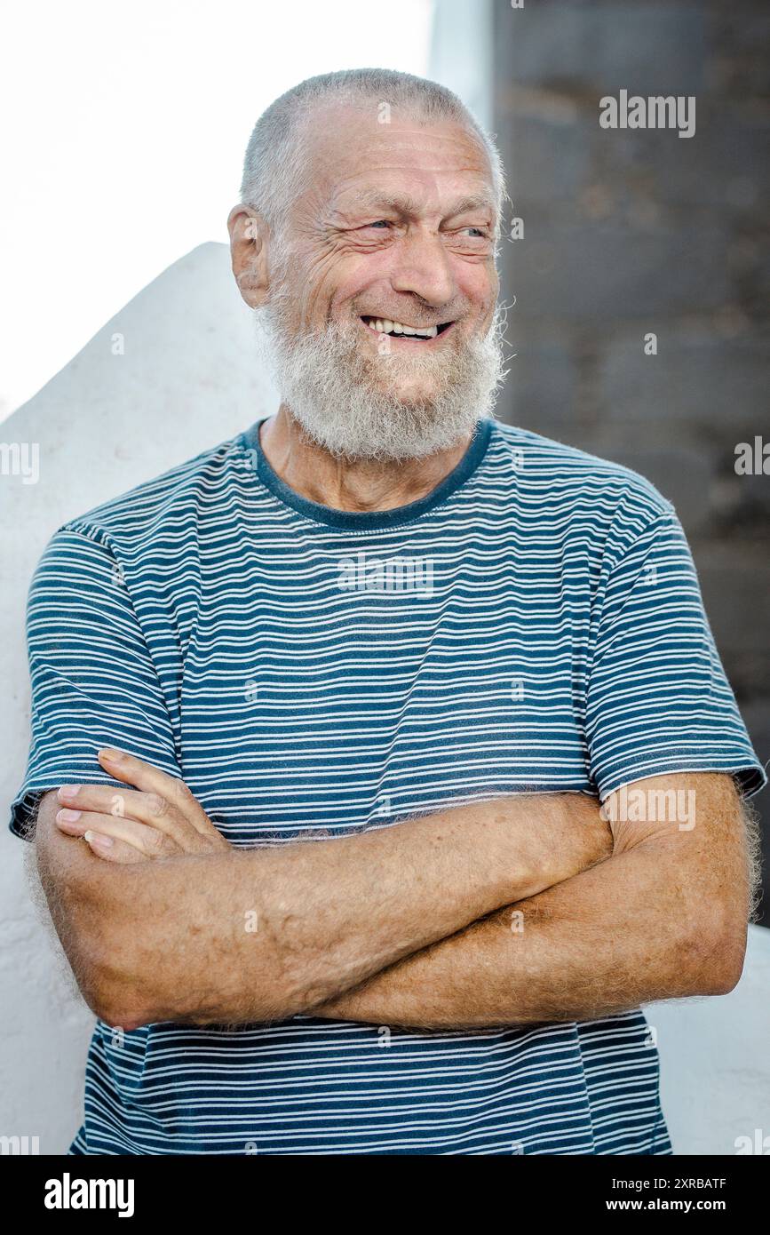 Der 75-jährige Seniorenmann lacht, während er sich draußen amüsiert. Stockfoto