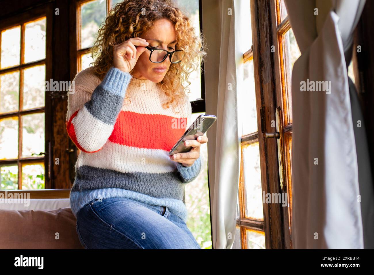 Eine erwachsene Frau, die allein bei der Online-Freizeitaktivität im Innenbereich zu Hause per Telefon liest und Nachrichten sendet Stockfoto