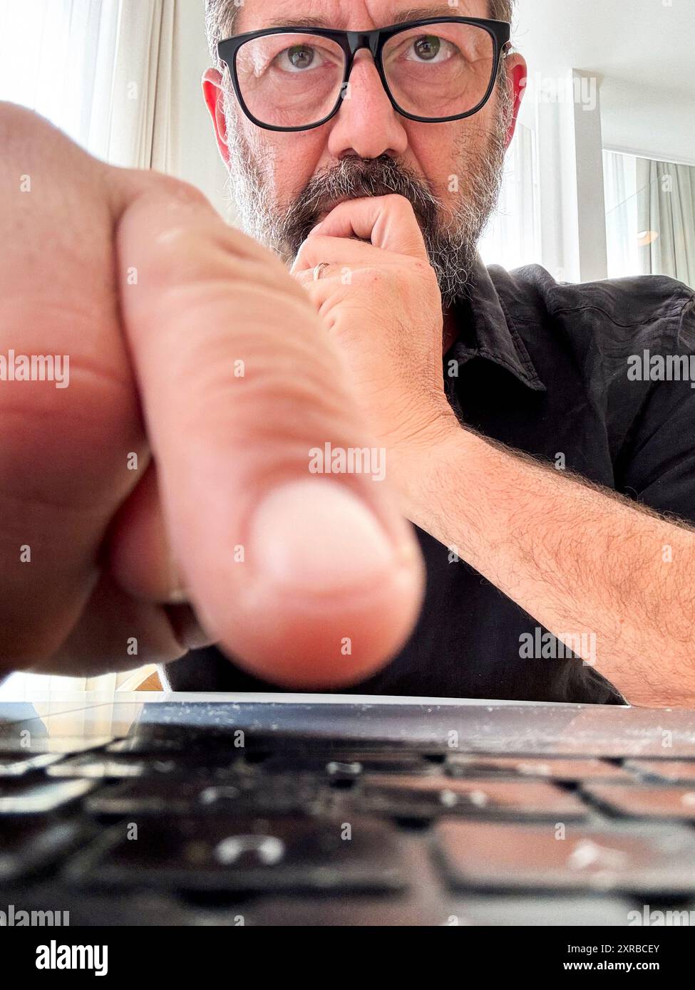 Mann, der auf die Tastatur klickt, um eine Bedingung mit Zweifeln und besorgtem Ausdruck anzunehmen oder abzulehnen. Betrug und Betrug, Datenschutzwarnung. Virenerkennung auf Laptop-Computer. Ein Online-Mitarbeiter denkt sich Sorgen Stockfoto