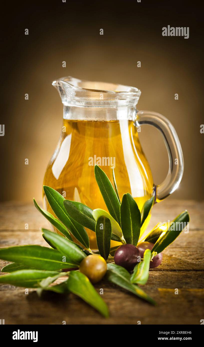 Flasche Olivenöl und einen Olivenzweig auf Holztisch Stockfoto