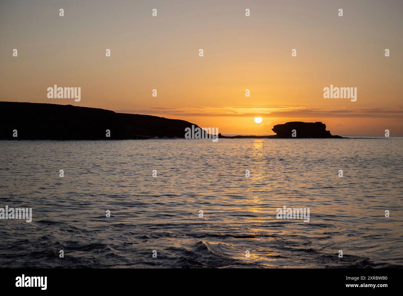 Blick auf den Sonnenaufgang über dem Atlantik. Blick über einen Steinstrand auf einer Vulkaninsel. Kalte Lavasteine am Meer am Strand von Playa Laja del Corral, Fuerteventura, Kanarischen Inseln, Spanien Stockfoto