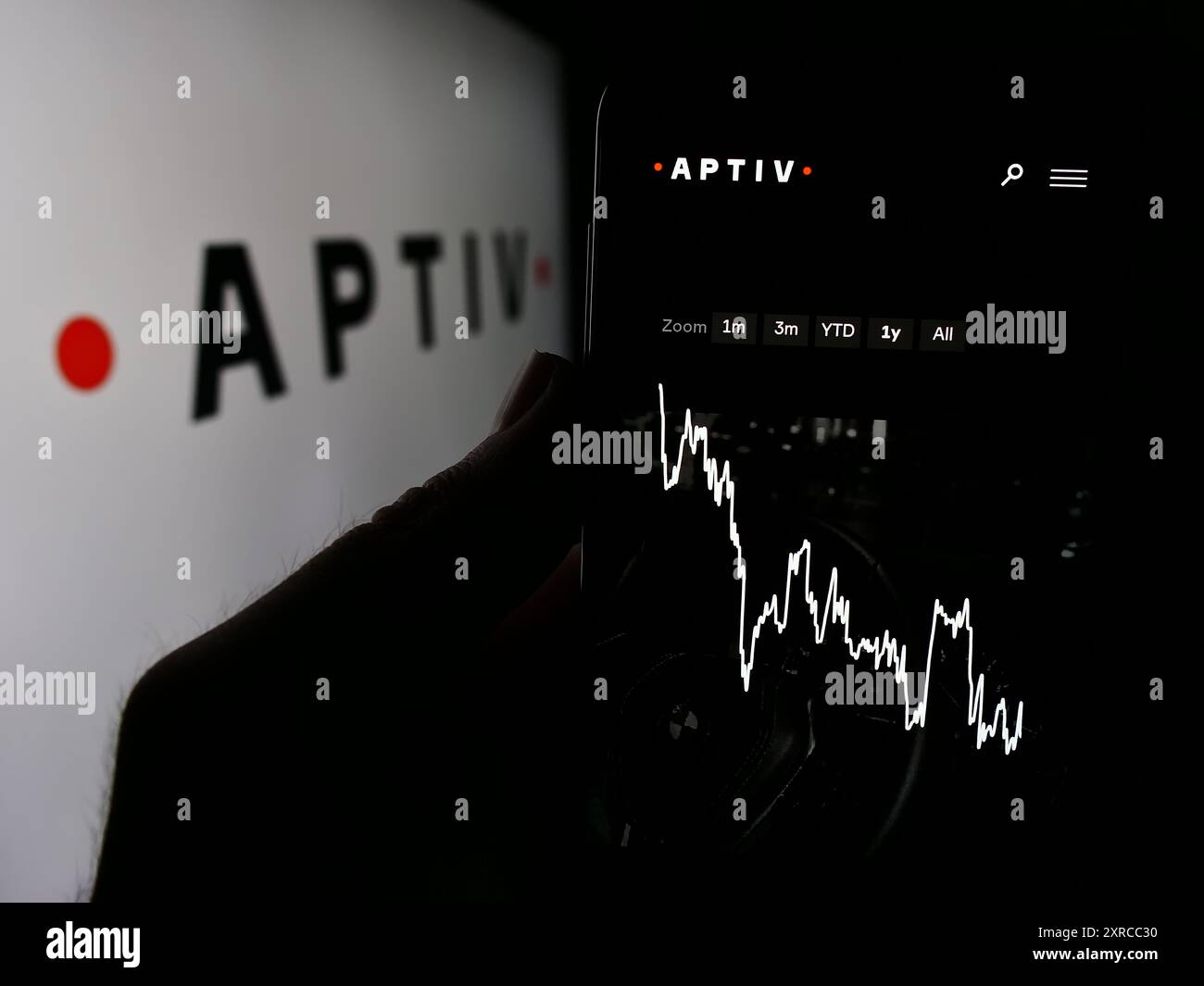 Person, die ein Mobiltelefon hält, mit der Webseite des Automobilhersteller Aptiv plc vor dem Geschäftslogo. Konzentrieren Sie sich auf die Mitte des Telefondisplays. Stockfoto