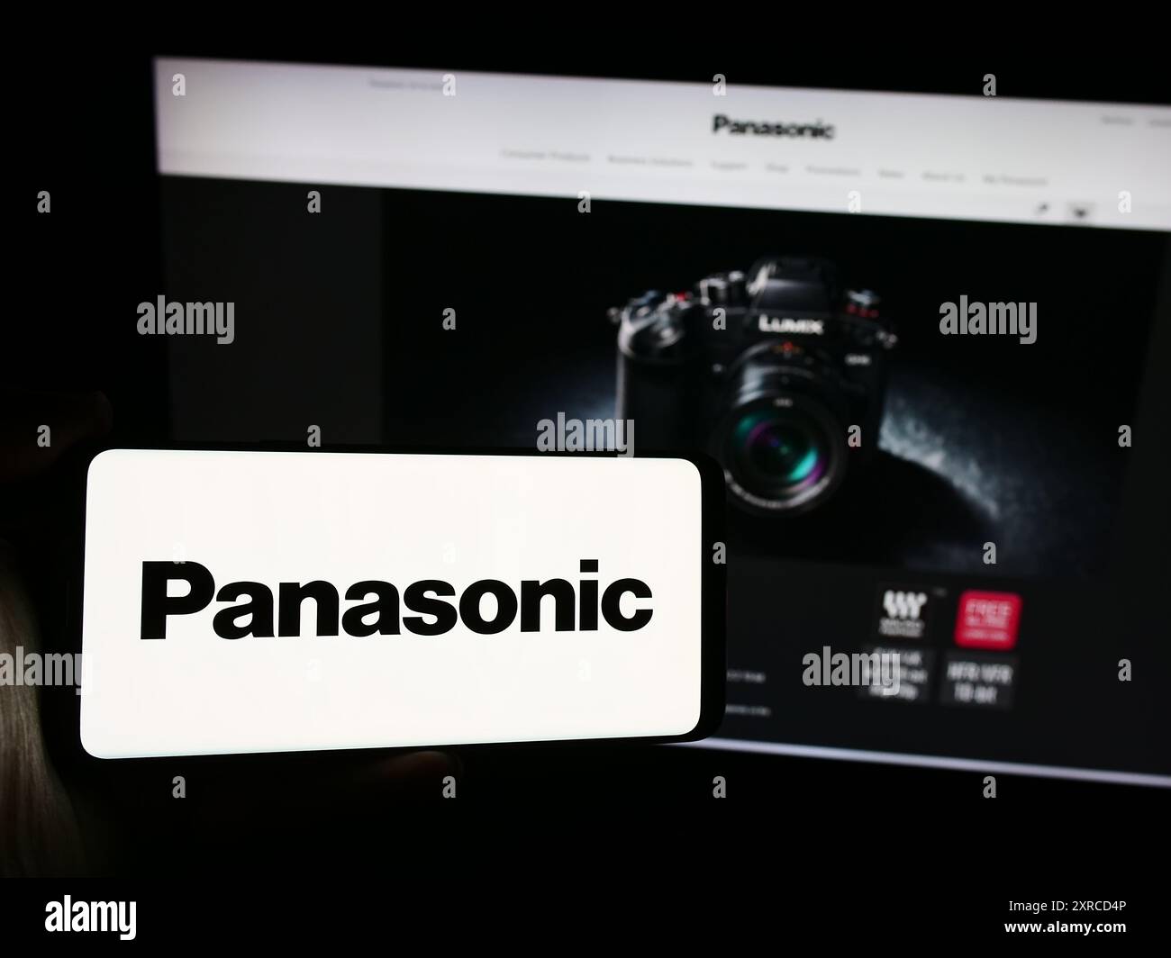 Person, die ein Smartphone mit dem Logo der japanischen Firma Panasonic Holdings Corporation vor der Website hält. Schwerpunkt auf dem Display des Telefons. Stockfoto