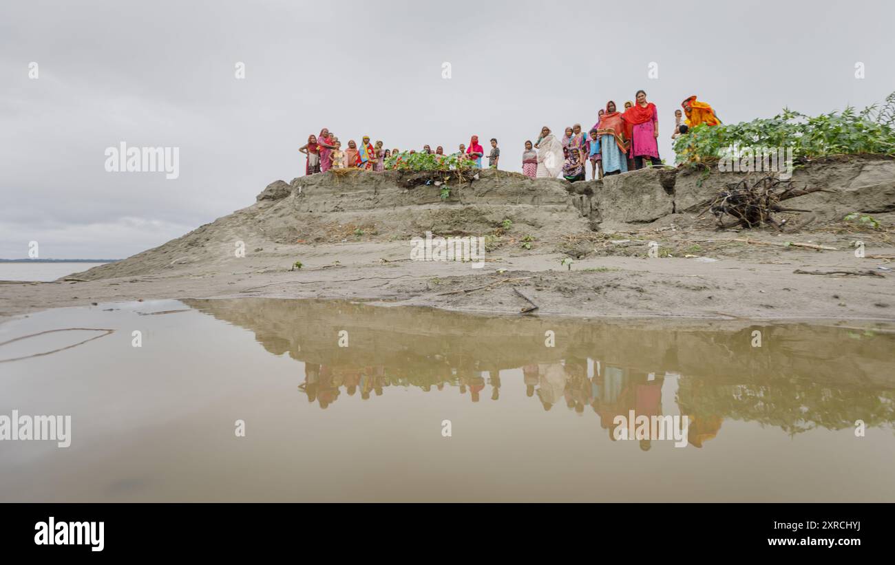 Frauen und Kinder der Nayer-Saibling am Flussufer des Brahmaputra River. Während und nach dem letzten Hochwasser spaltete der Fluss den Saibling fast in die Hälfte und spülte riesige Landflächen weg. Stockfoto