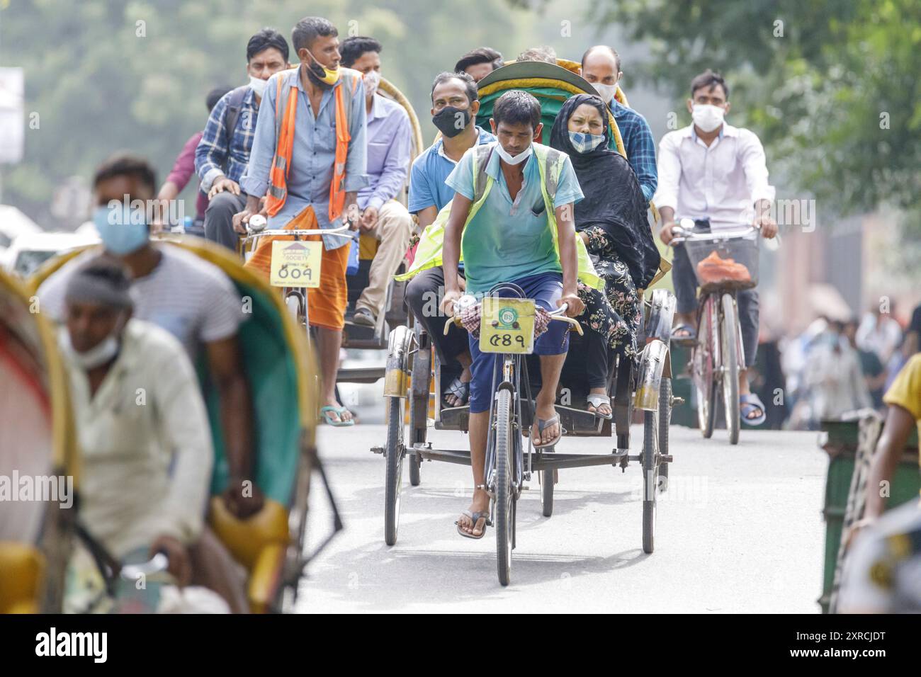 Am Dienstag, den 12. Juli, laufen oder reiten Menschen auf dem Weg zur Arbeit im Morgenrausch in Dhaka. Bangladesch durchlebt einen Anstieg von COVID-19, mit einem Rekordhoch von 13768 Fällen am Montag, dem 12. Juli. Am 14. Juli werden die Sperrbeschränkungen für neun Tage für die Eid-ul-Azha-Feierlichkeiten aufgehoben. Stockfoto