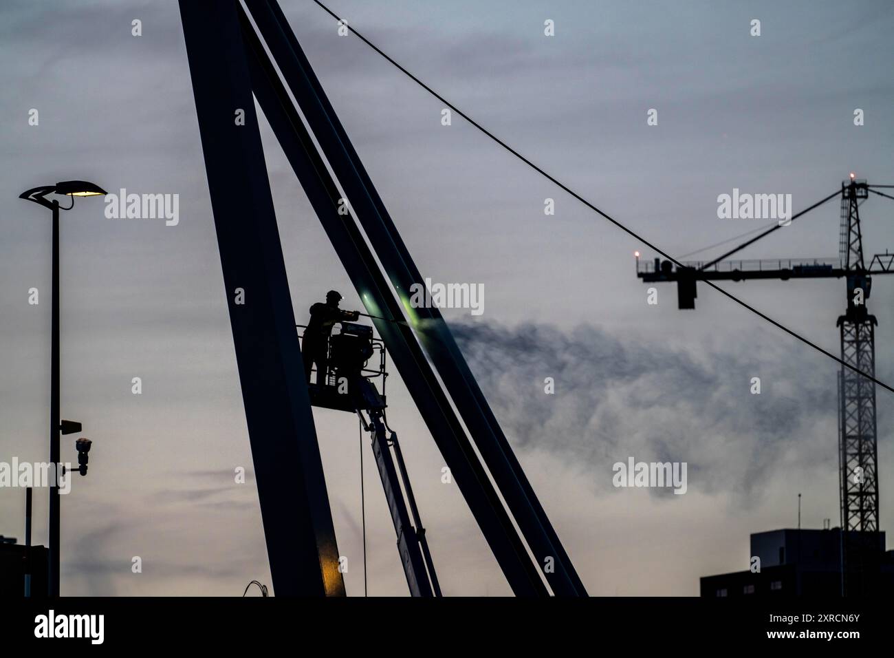 Arbeiter reinigt einen Brückenpier mit einem Hochdruckreiniger auf einem Kirschpflücker an der Erasmus-Brücke über die Nieuwe Maas in Rotterdam, Niederlande Stockfoto