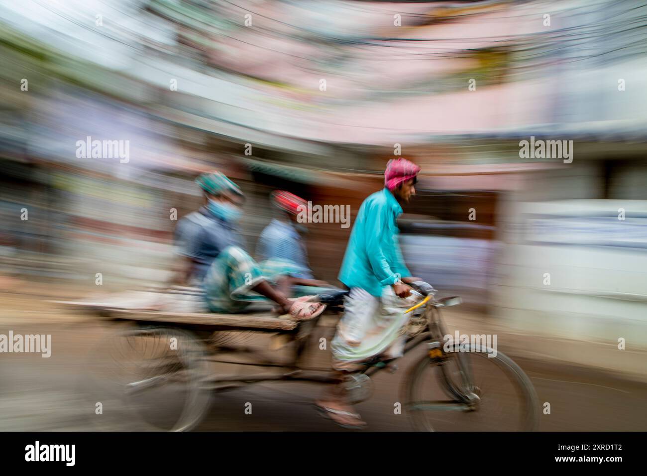 Rikscha-Abzieher auf den Straßen von Puran Dhaka - Old Dhaka in Bangladesch. Die Rikschas sind pedalbetriebene Dreiräder, wurden aber früher von Hand gezogen, daher 'Rikschas-Abzieher'. Heutzutage werden viele der Rikschas sogar auf Elektromotor umgerüstet. Stockfoto