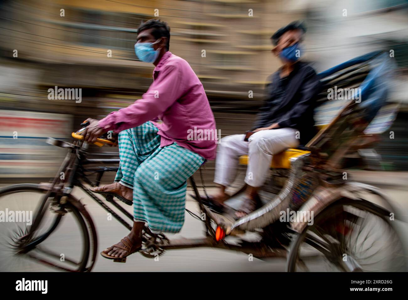 Rikscha-Abzieher auf den Straßen von Puran Dhaka - Old Dhaka in Bangladesch. Die Rikschas sind pedalbetriebene Dreiräder, wurden aber früher von Hand gezogen, daher 'Rikschas-Abzieher'. Heutzutage werden viele der Rikschas sogar auf Elektromotor umgerüstet. Stockfoto