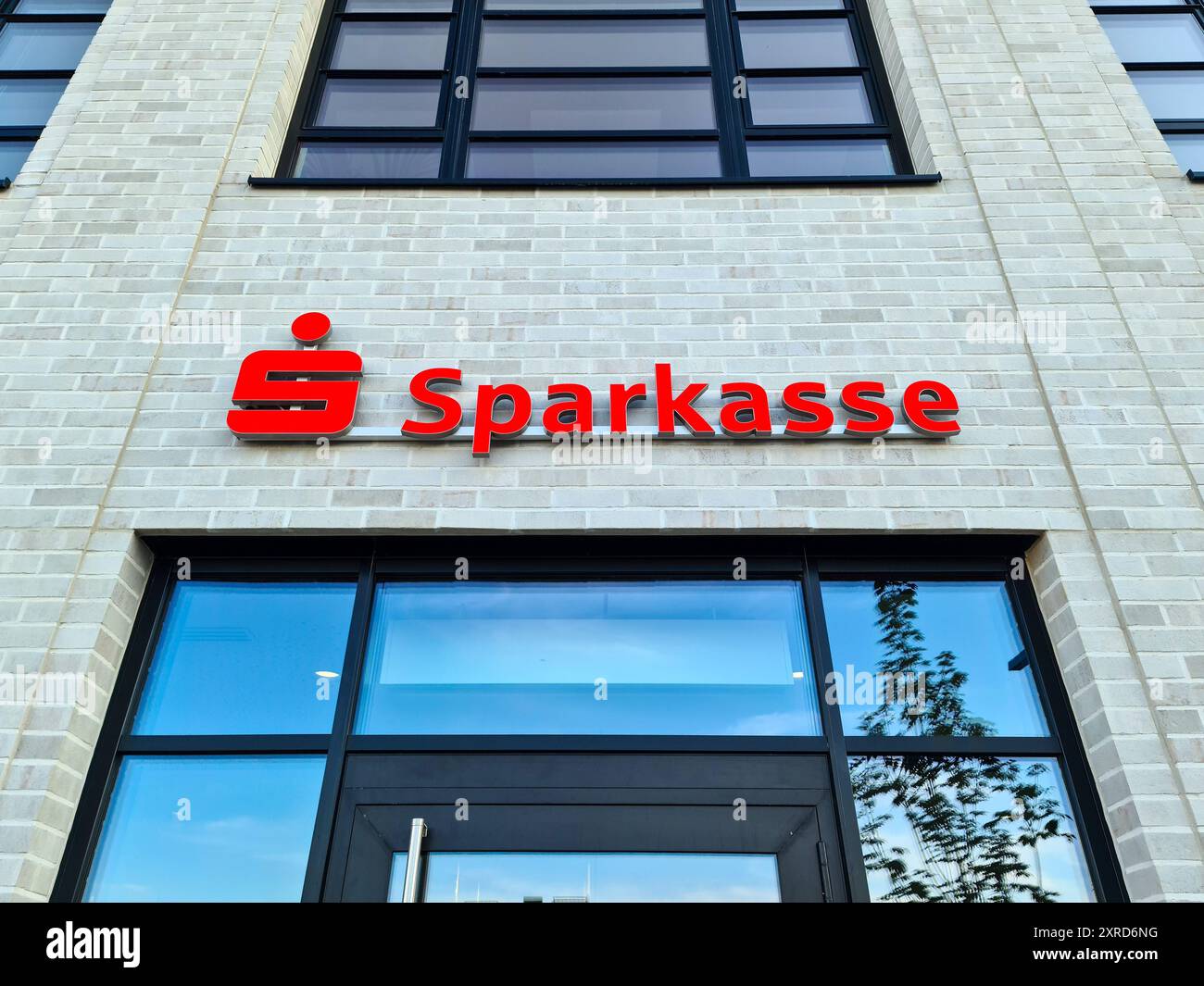 Köln, Deutschland - 08. August 2024: Der Eingangsbereich einer Bankfiliale mit dem Namen Sparkasse mit dem roten Logo über dem Eingang Stockfoto