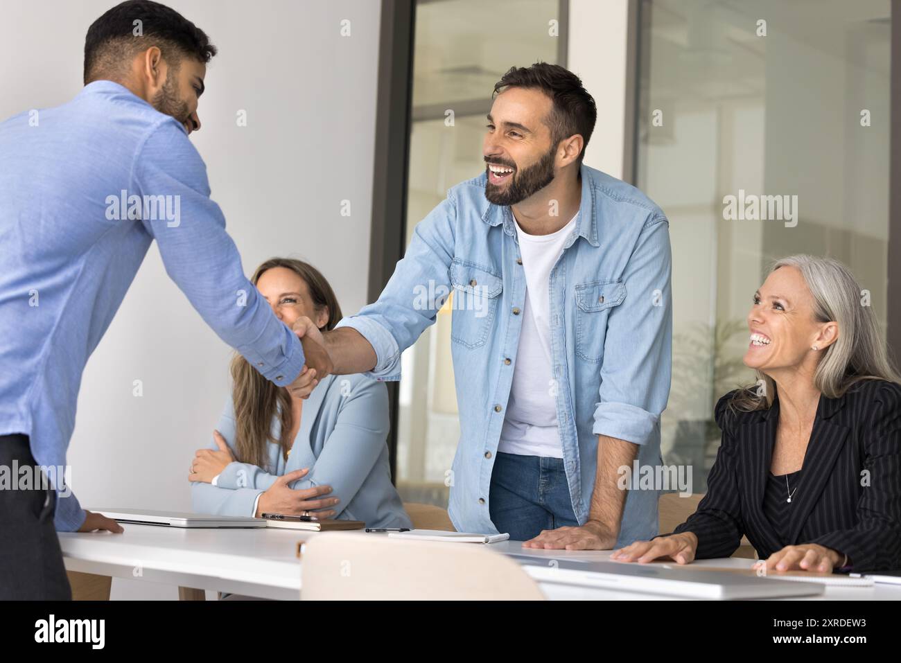 Glückliche Geschäftsmänner, die sich zwanglos die Hände schütteln, bei Firmenbesprechungen Stockfoto