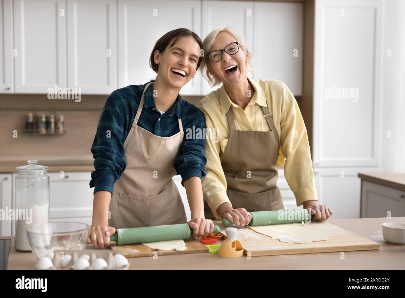 Glückliche jüngere und ältere Bäckerinnen, die hausgemachtes Gebäck zubereiten Stockfoto