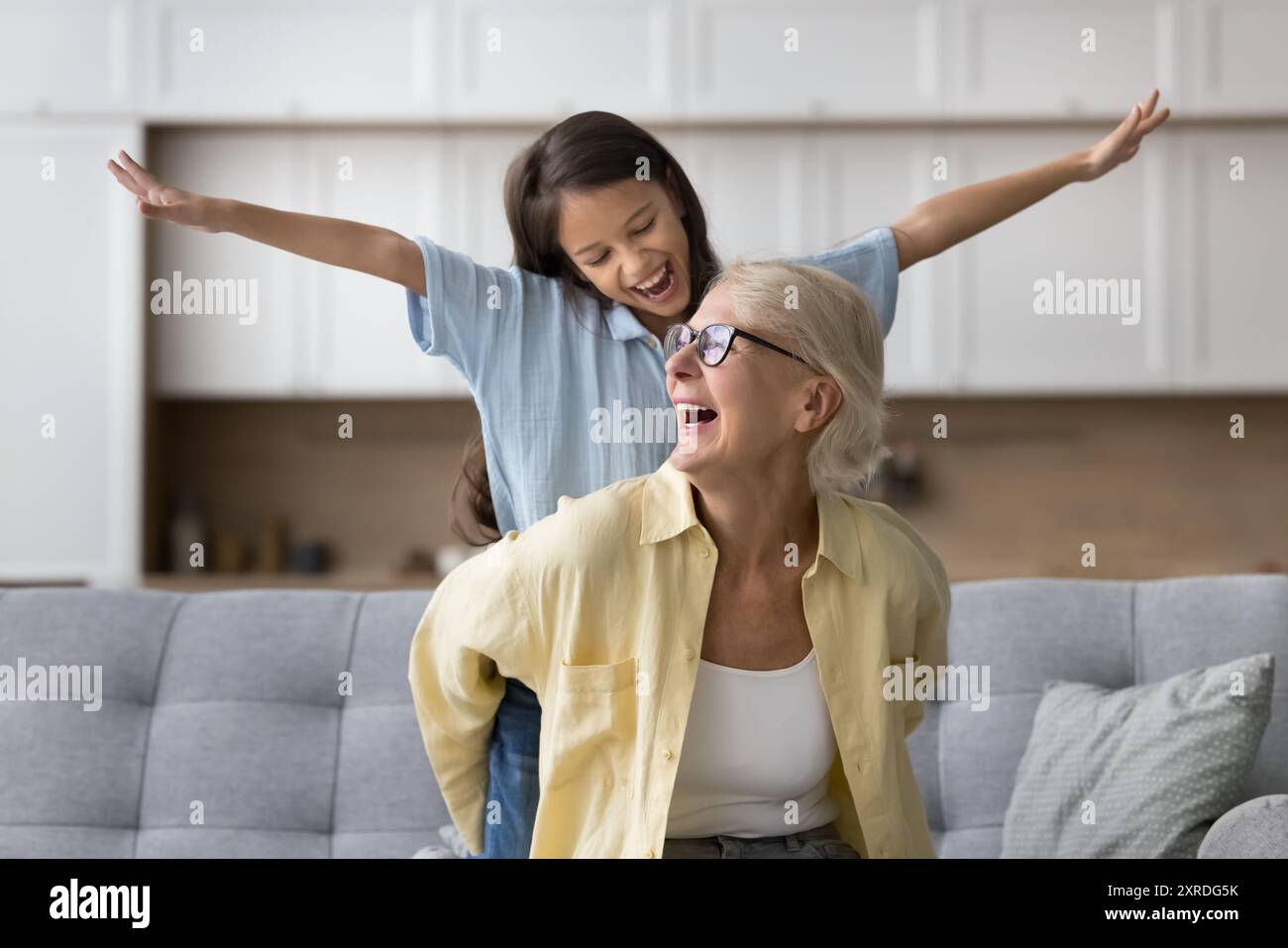 Glücklich aufgeregt, starke Großmutter, die Enkelin, die auf dem Sofa sitzt Stockfoto
