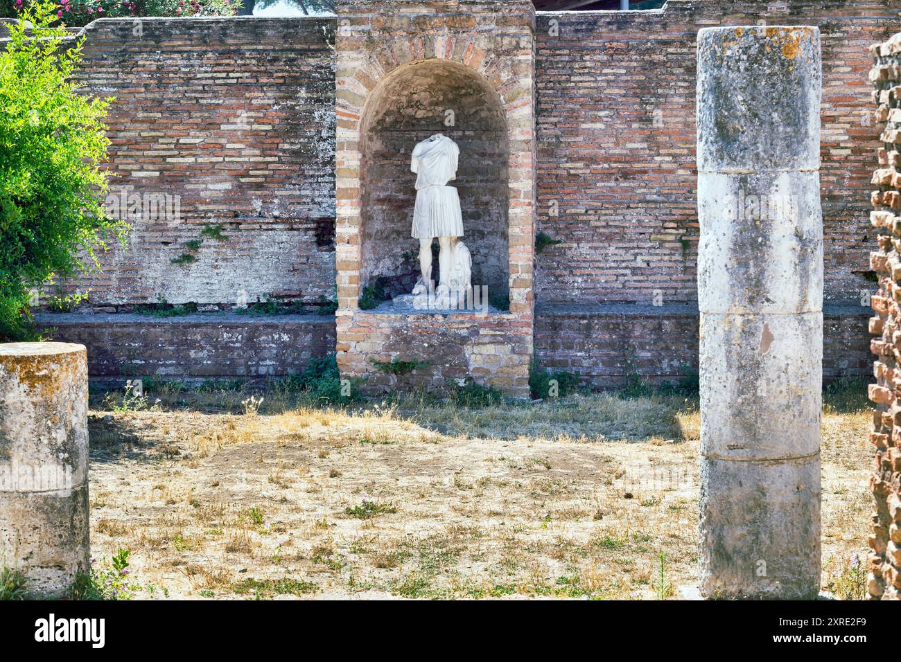 Innenhof des Domus della Fortuna Annonaria mit Ruinen römischer Säulen und Statue der Göttin Diana im archäologischen Gebiet von Ostia Antica - R Stockfoto