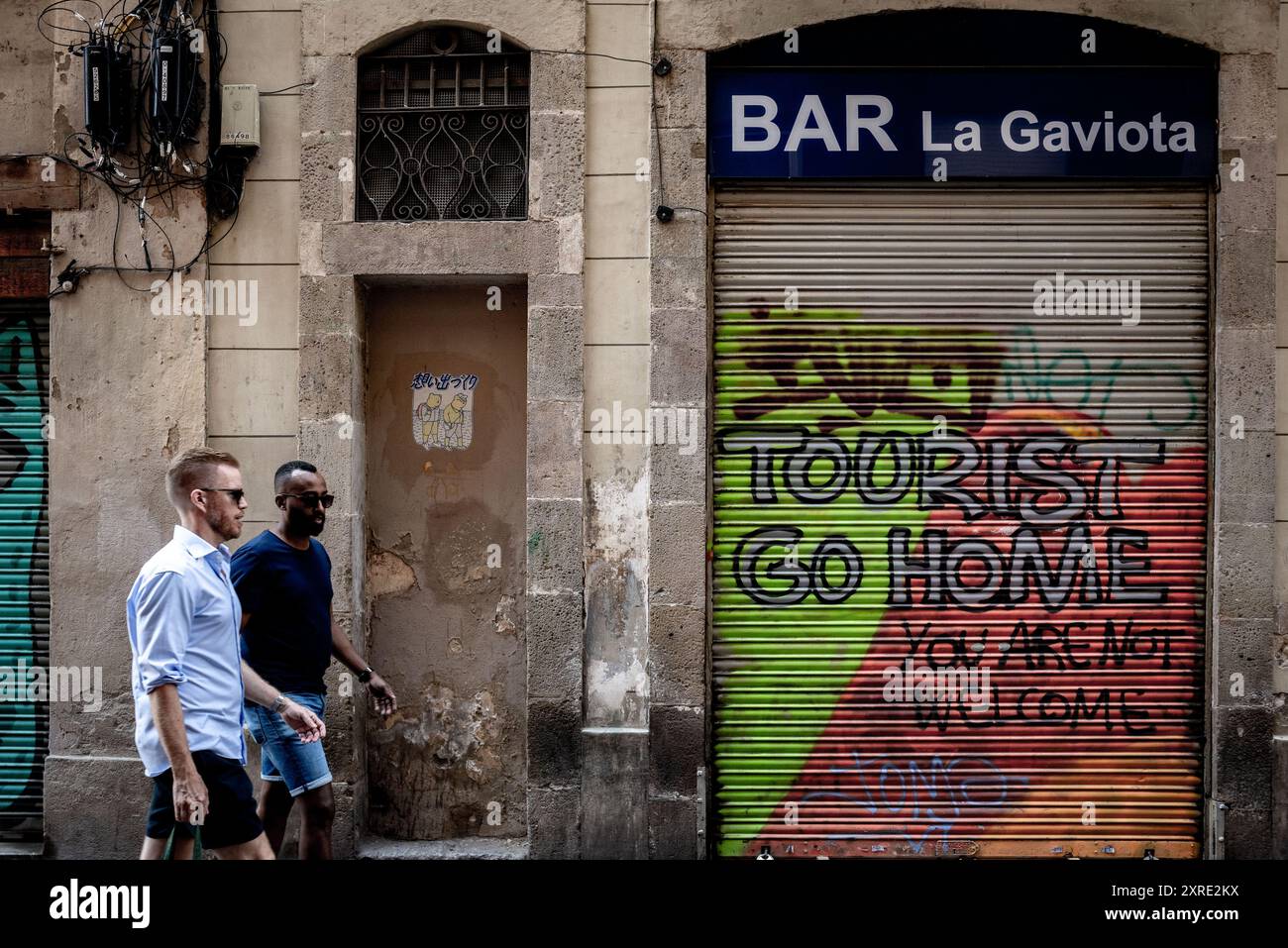 In Barcelonas Stadtteil Gracia laufen die Menschen an einem Anti-Tourismus-Graffiti vorbei, das heißt: "Touristen, geh nach Hause". Stockfoto