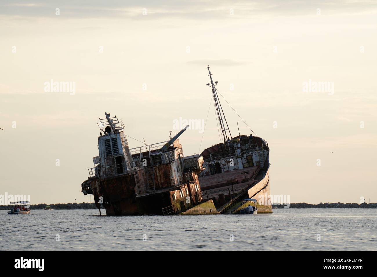 Rostiges Schiffswrack mit Möwen und Tourboot bei Sonnenuntergang, Schwarzes Meer, Rumänien Stockfoto