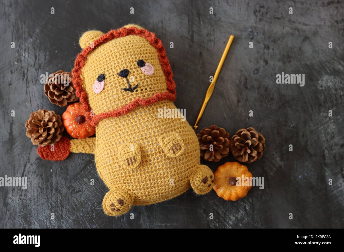 Kuschelspielzeug mit gehäkeltem Löwen aus nächster Nähe. Niedliche handgemachte Teppichpuppe auf dunklem strukturiertem Hintergrund mit Kopierraum. Stockfoto