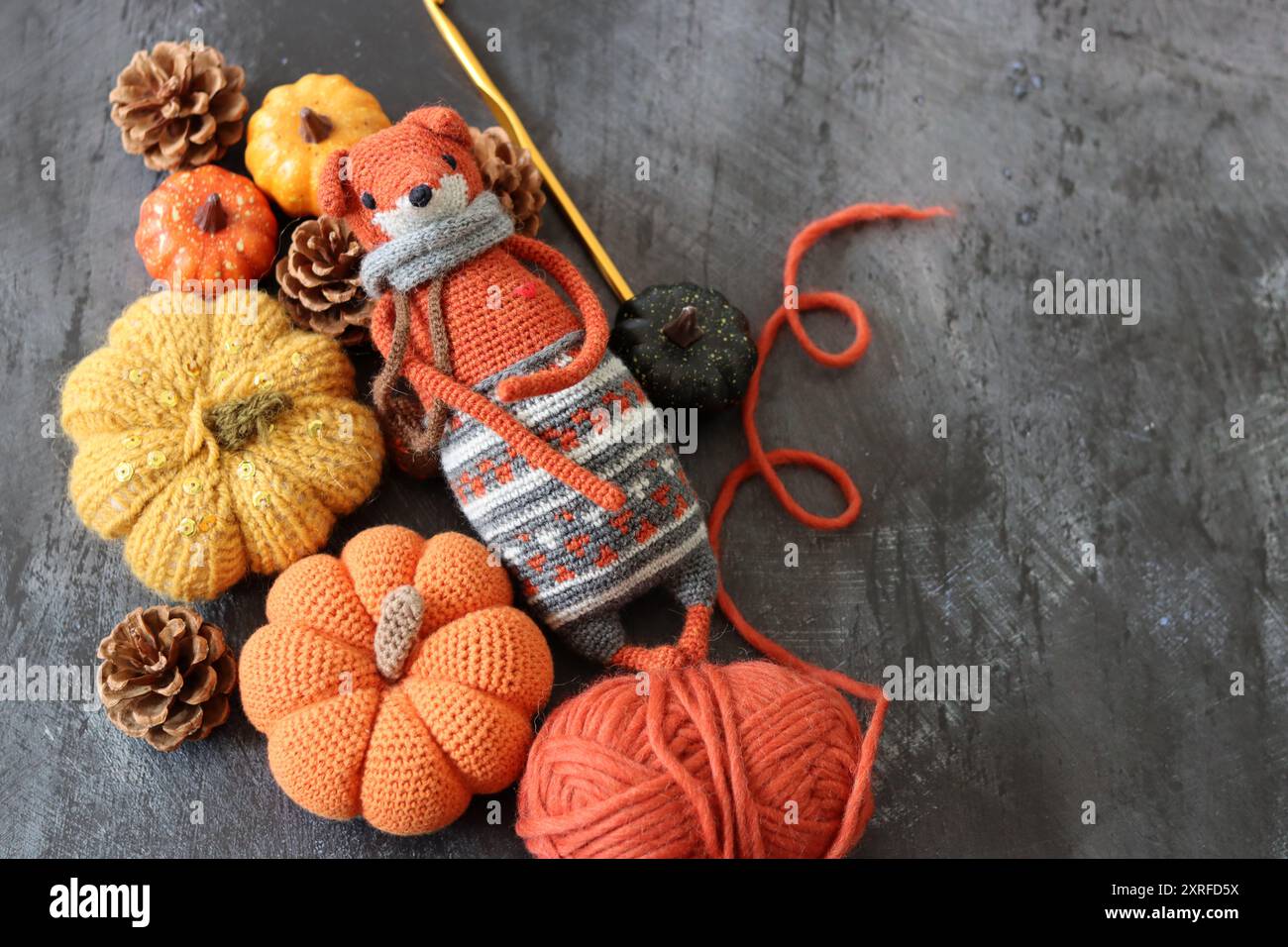 Halloween-Dekoration mit Kürbissen, gehäkeltem Fox-Spielzeug und orangenem Wollgarn auf grauem Hintergrund mit Platz für Text. Handgefertigtes Herbstgeschenk. Stockfoto
