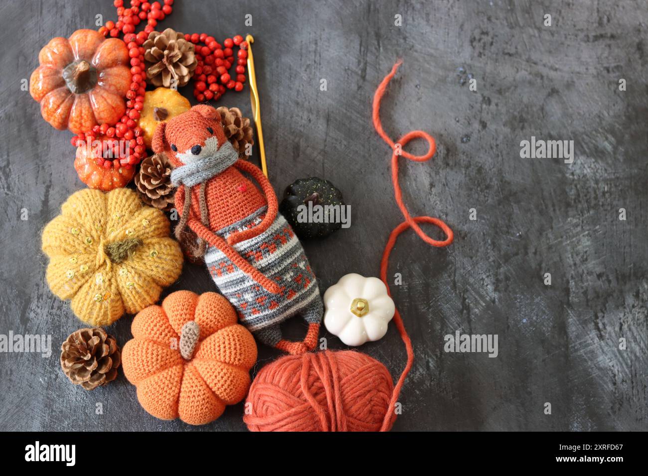 Halloween-Dekoration mit Kürbissen, gehäkeltem Fox-Spielzeug und orangenem Wollgarn auf grauem Hintergrund mit Platz für Text. Handgefertigtes Herbstgeschenk. Stockfoto