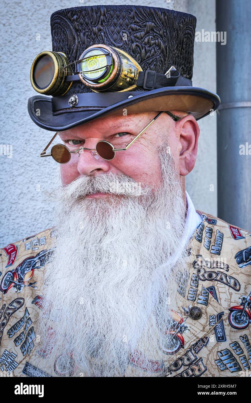 Henrichenburg, Waltrop, Deutschland. August 2024. Ein viktorianischer Biker mit Top-Hut. Steampunk-Fans, Gruppen und Besucher, viele davon in Retro-futuristischen oder viktorianischen Kostümen, haben am ersten Tag des jährlichen Steampunk Jubilee Festivals und Markts Spaß. In diesem Jahr fällt das Festival mit dem 125-jährigen Jubiläum der historischen Henrichenburger Bootsliftanlage zusammen, einem denkmalgeschützten Industriedenkmal entlang des Dortmund-Ems-Kanals. Quelle: Imageplotter/Alamy Live News Stockfoto