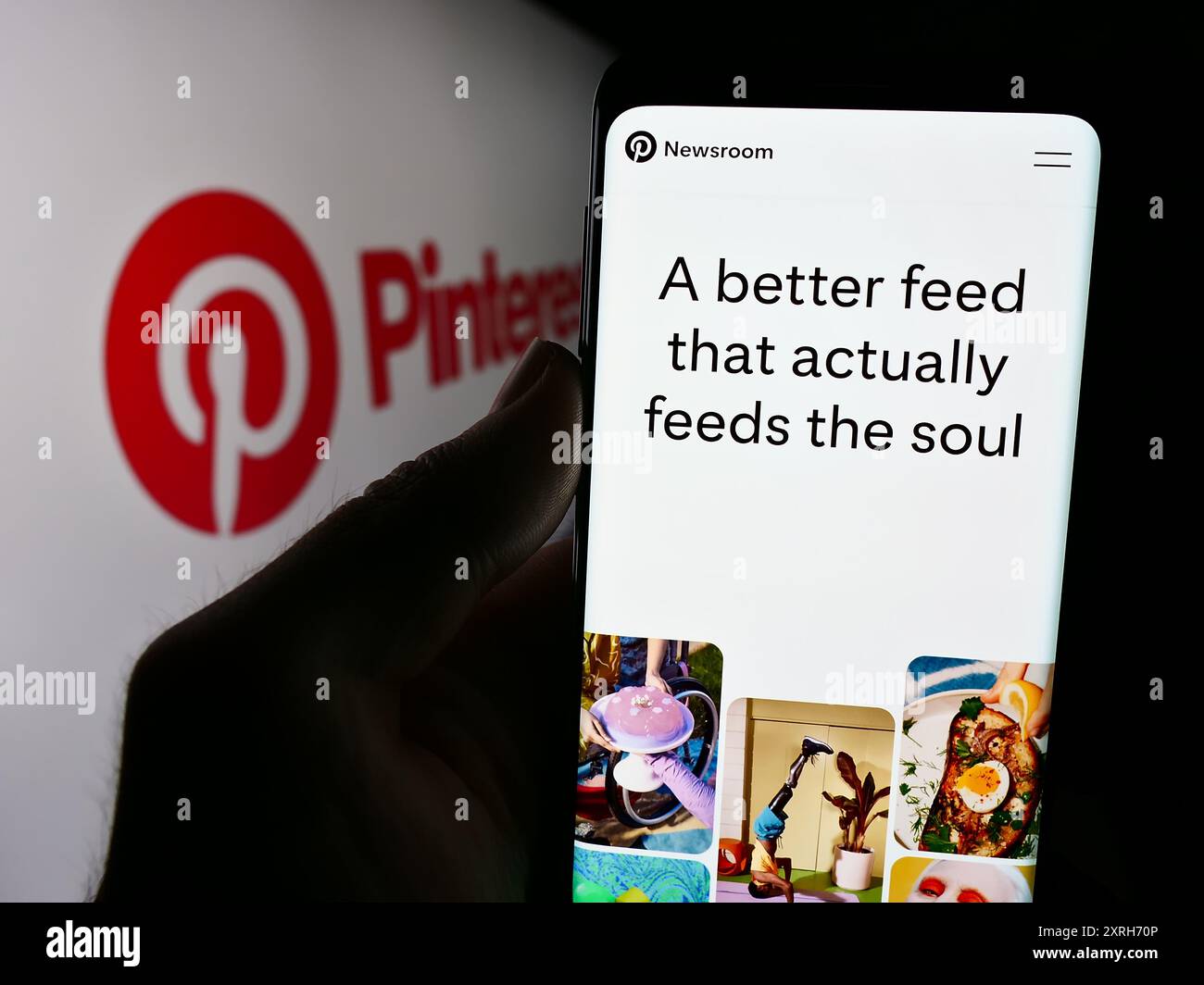 Person, die ein Mobiltelefon hält, mit der Webseite des US-amerikanischen Social-Media-Unternehmens Pinterest Inc. Vor dem Firmenlogo. Konzentrieren Sie sich auf die Mitte des Telefondisplays. Stockfoto